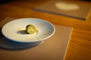 A cute gherkin slice with a smiley face on a white plate, perfect for quirky food projects.